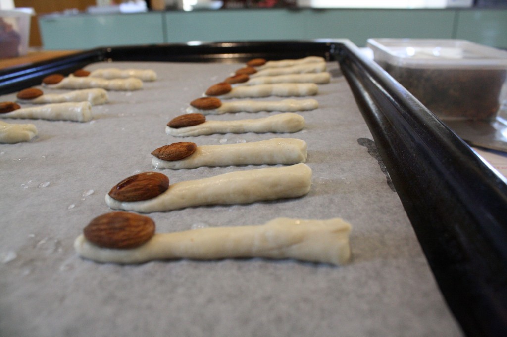 I rolled a little of each piece of dough into a 'finger' , dipped it into the bicarb, placed it on the tray and pressed an almond into the thinner end.